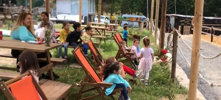 Gölgelikli bahçede şezlonglarda aileler ve çocuklar
