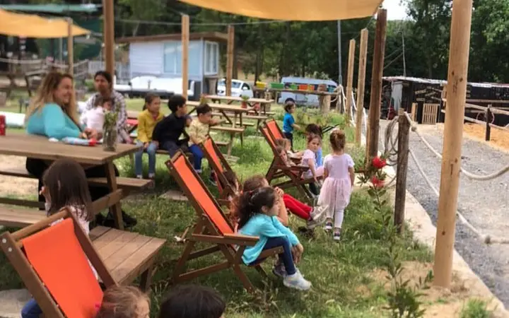 Gölgelikli bahçede şezlonglarda aileler ve çocuklar