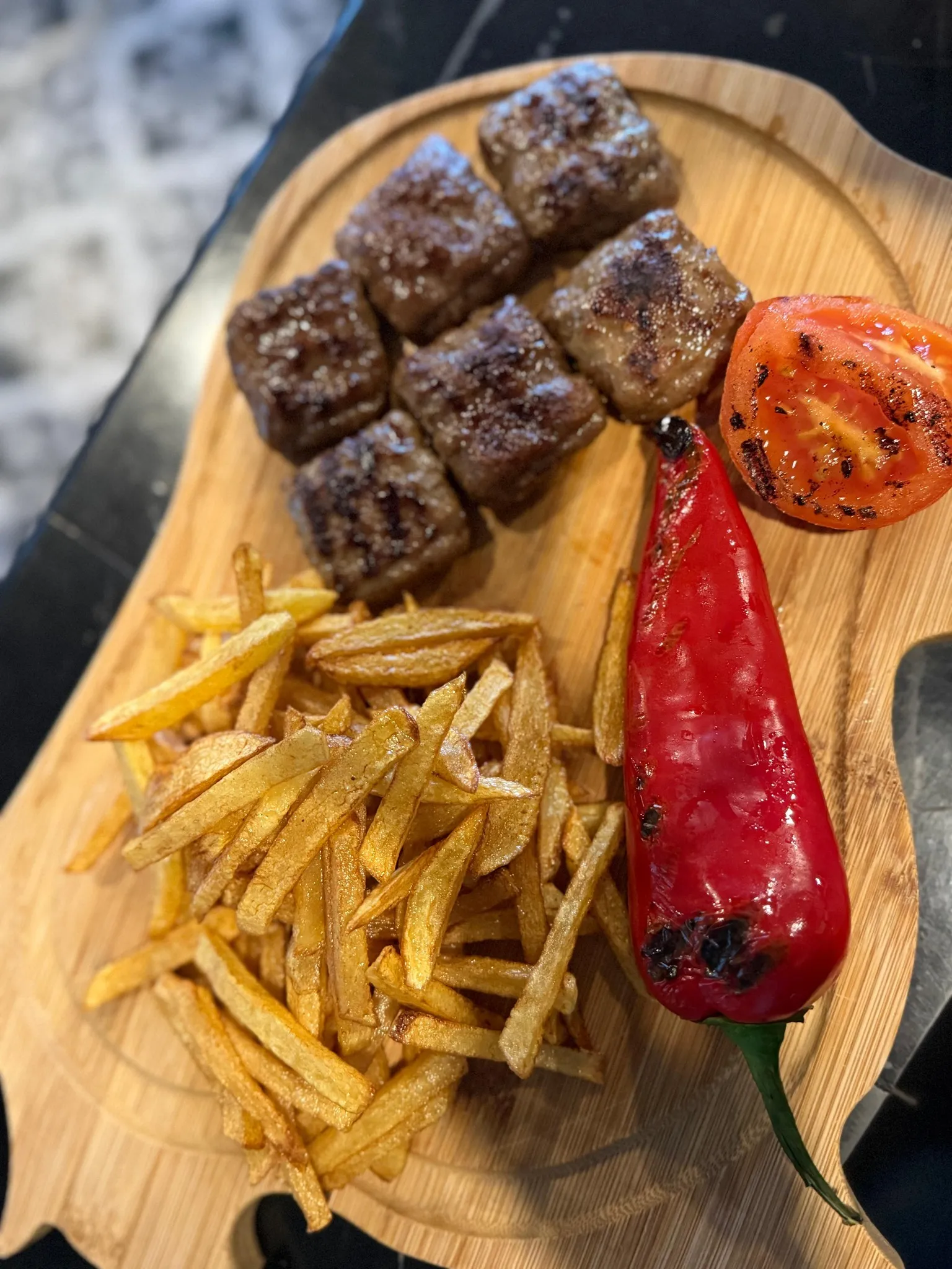 Ahşap tahtada köfte, patates ve köz biber